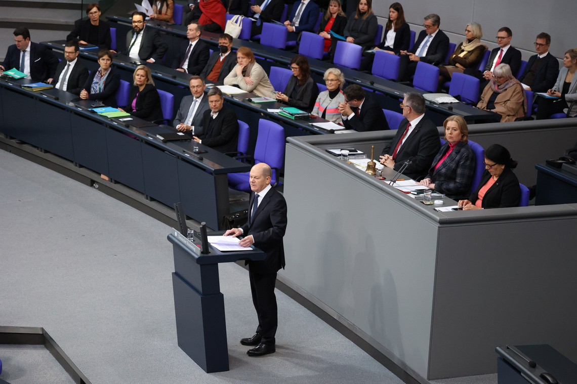 Bundeskanzler Olaf Scholz am Rednerpult des Plenarsaals, im Hintergrund die Regierungsbank