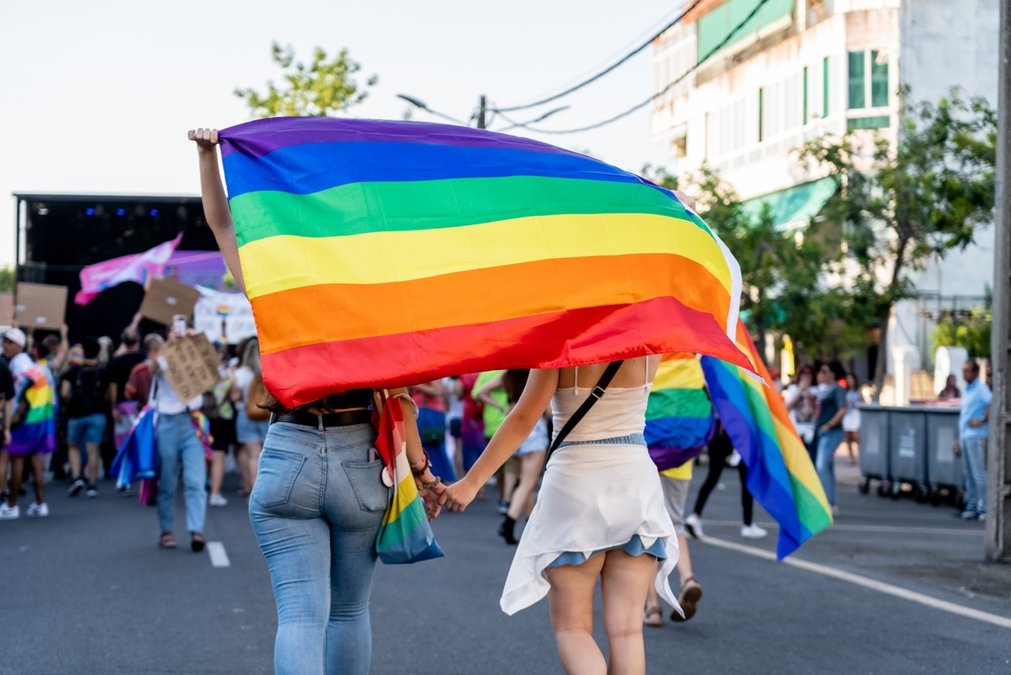 Zwei Menschen halten ihr Hände mit Regenbogenfahne in der Hand