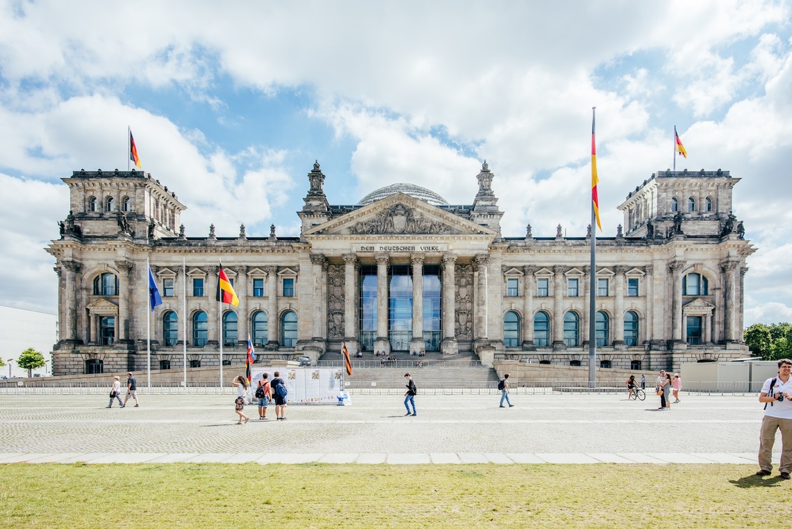 Aufnahme des Deutschen Bundestages von außen. Im Vordergrund spazierende Menschen.
