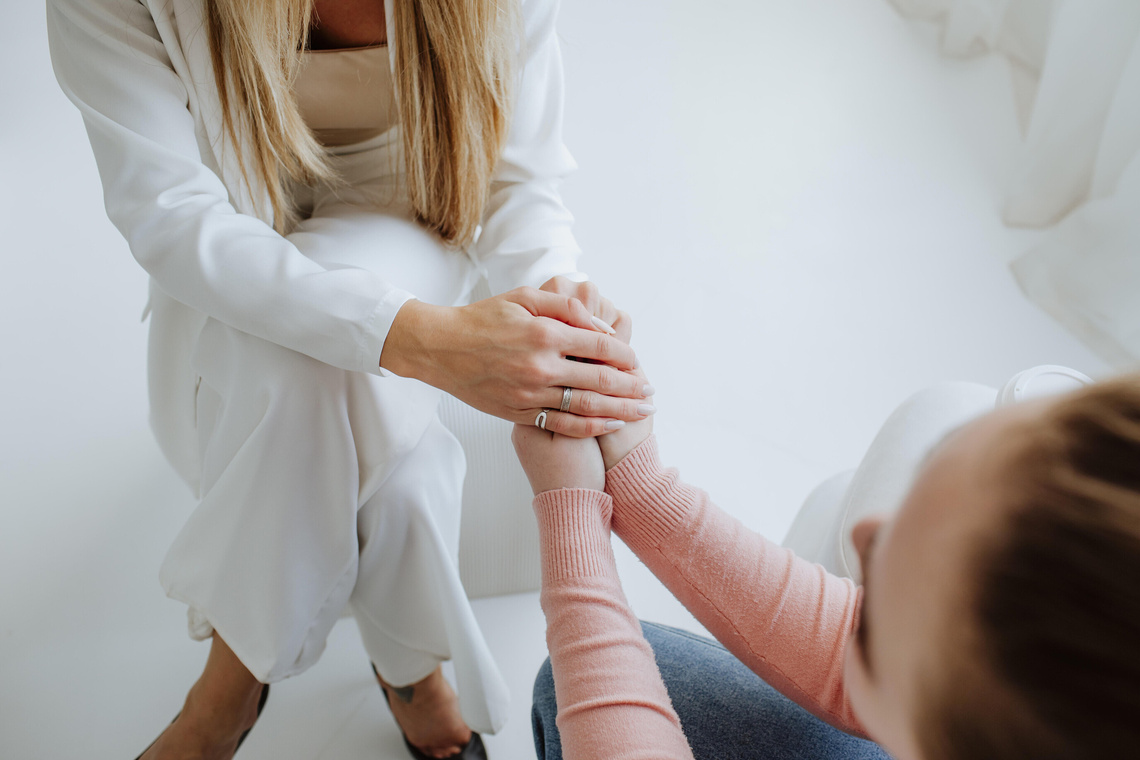 Hände von erwachsener Frau halten Hände von jungem Mädchen