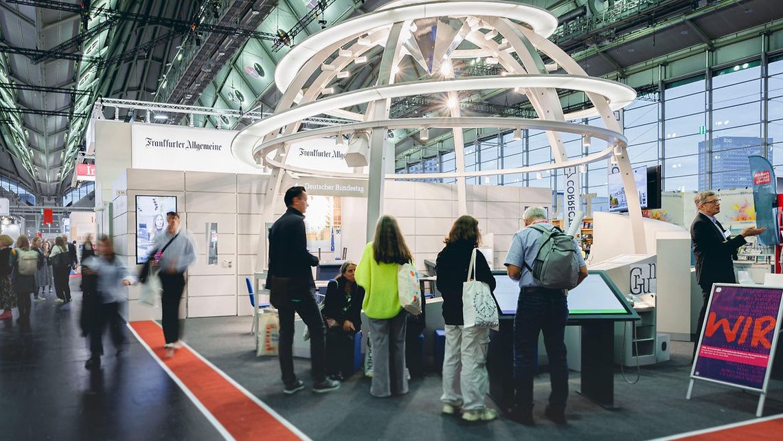 Messestand vom Bundestag mit einer nachgebauten Reichstagskuppel und Menschen am Stand