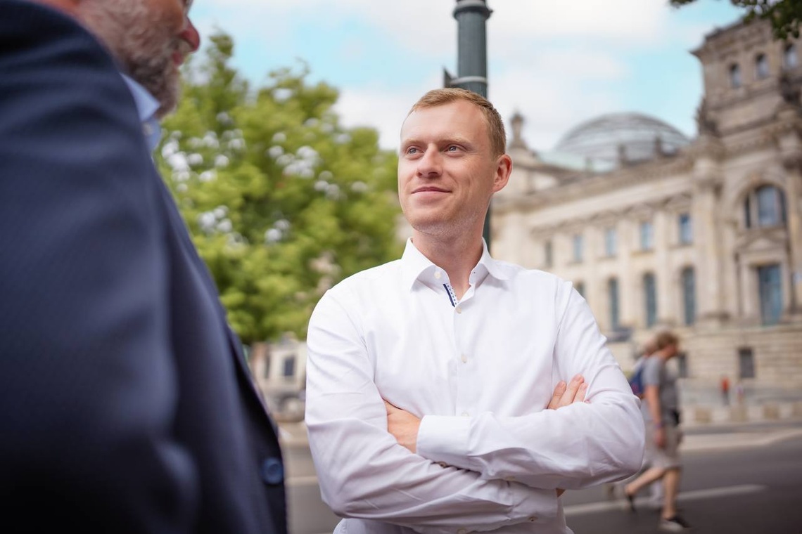 Jan Wenzel Schmidt sitzt vor dem Reichtagsgebäude.