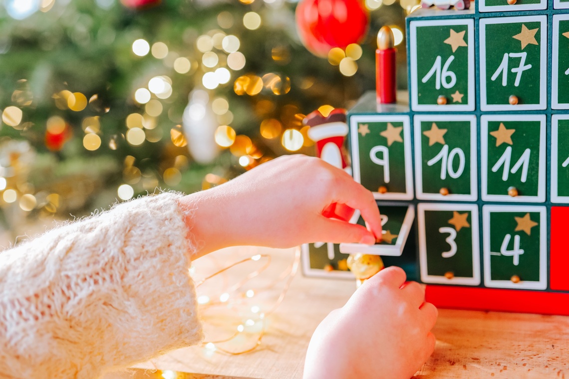 Eine Kinderhand öffnet ein Türchen an einem Adventskalender.