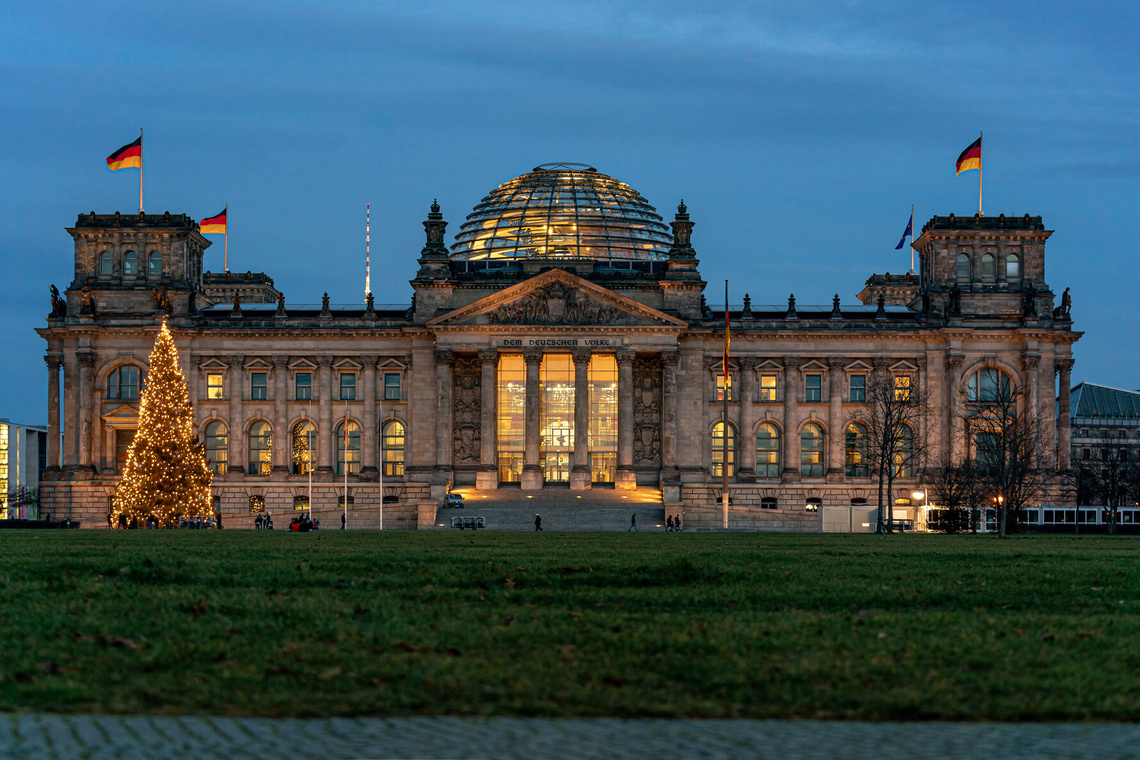 Reichstagsgebäude am Abend mit Weihnachtsbaum davor