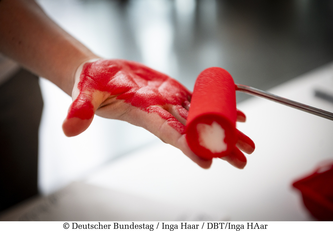 Rote Farbrolle färbt Hand rot ein