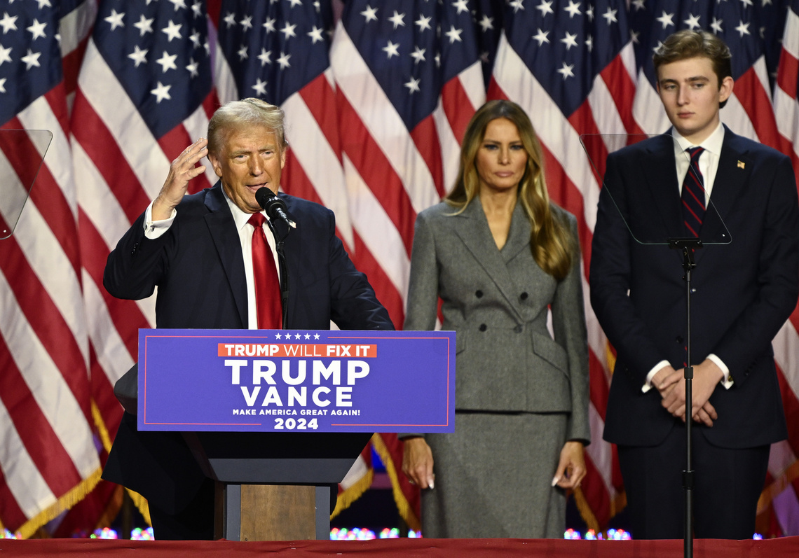 Donald Trump steht mit seiner Familie vor auf einer Bühne mit amerikanischen Flaggen und hält eine Rede.