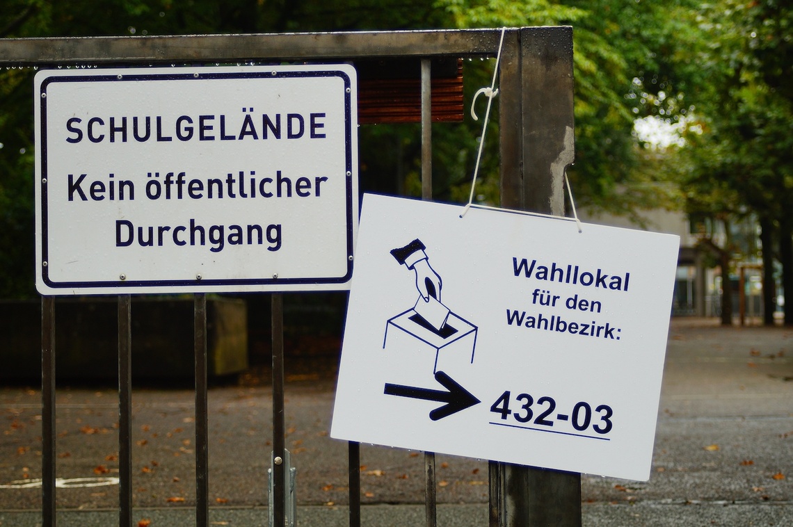 Links ein Schild "Schulgelände", rechts daneben ein Schild "Wahllokal"