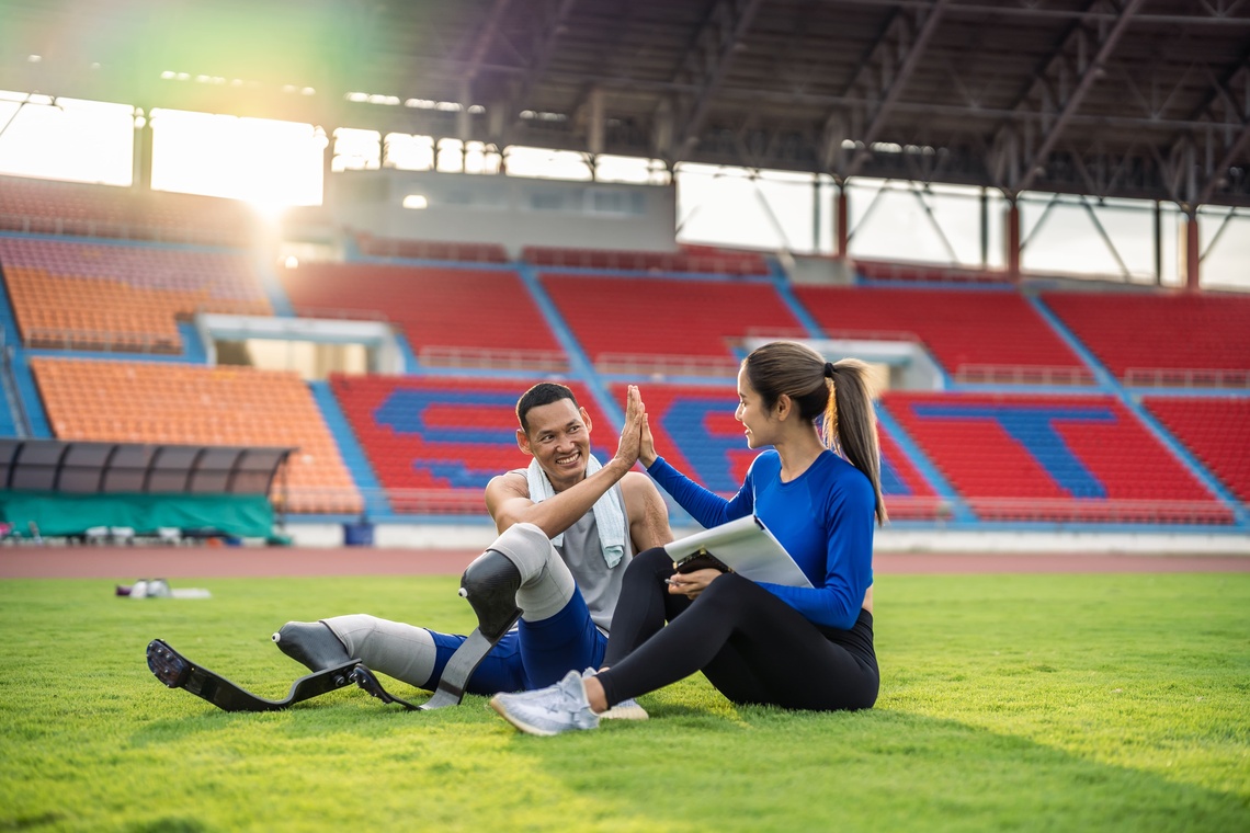 Ein Sportler mit Beinprothesen und seine Trainerin beim Training.