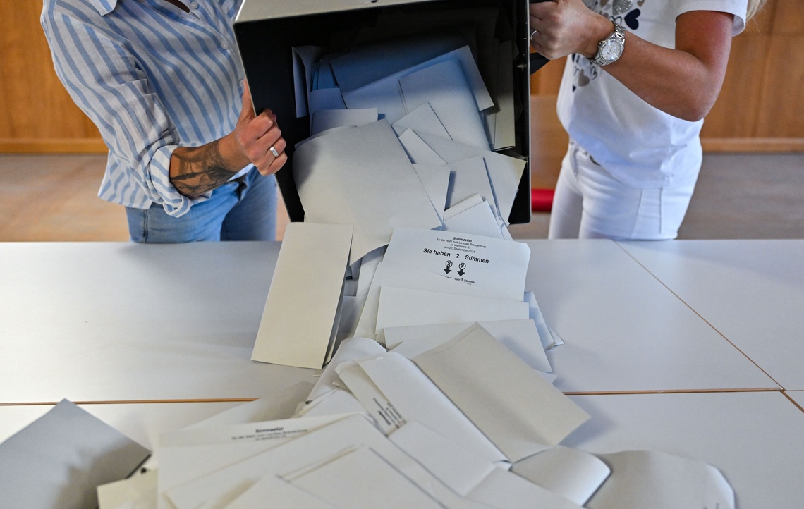 Wahlurne wird ausgeschüttet und Stimmzettel liegen auf dem Tisch verteilt.