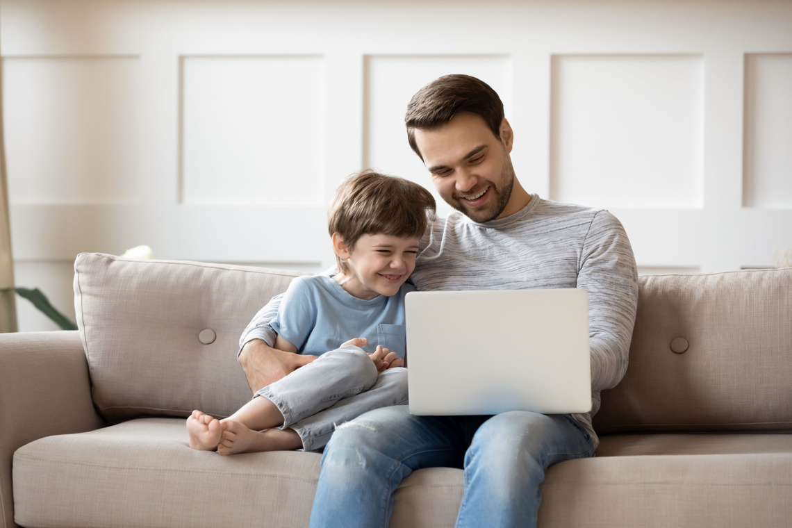 Mann und Junge schauen auf einen Laptop