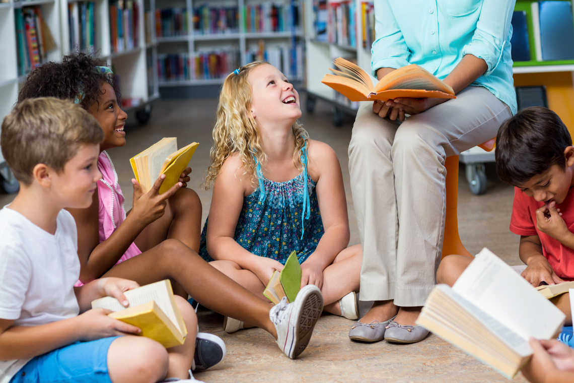 Lehrerin mit Kindern, die ein Buch lesen