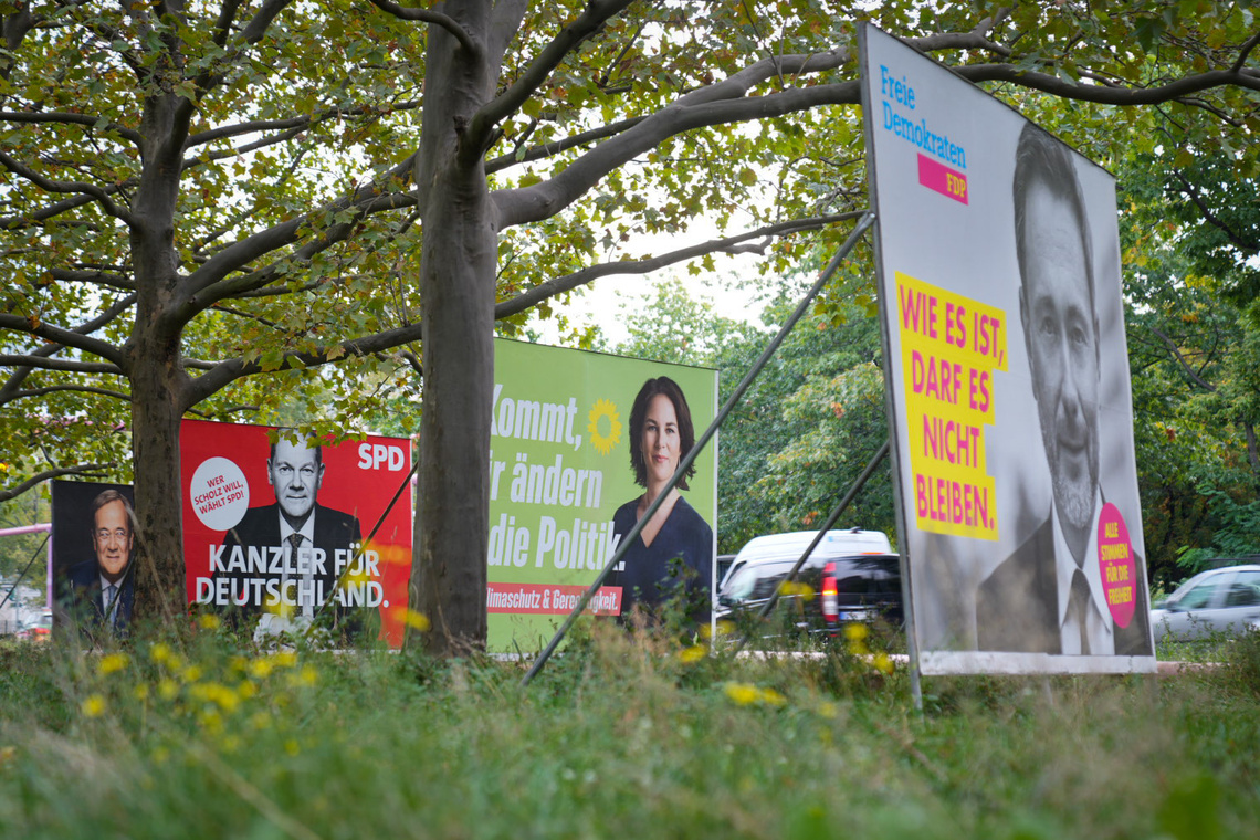 Wahlplakate verschiedener Parteien zwischen Bäumen