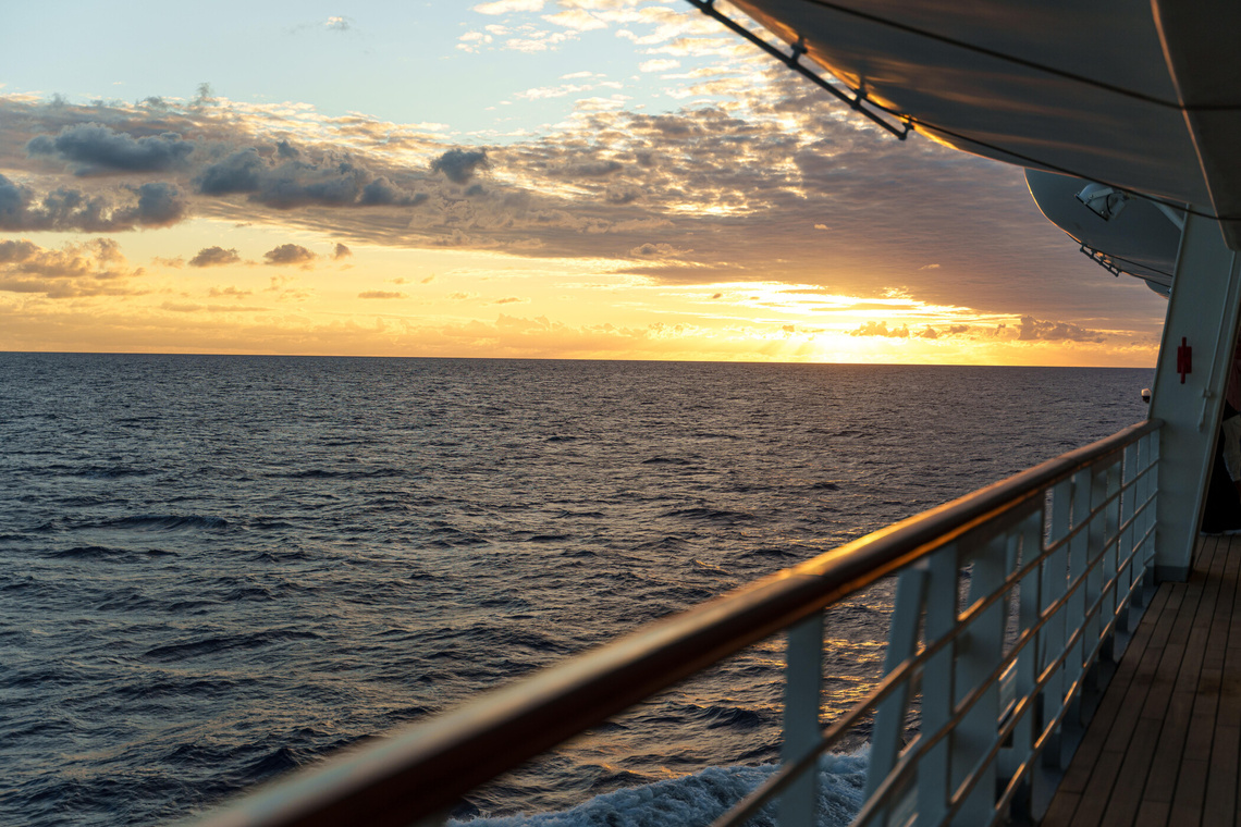 Sonne geht im Meer unter, Blick über eine Schiffsreling