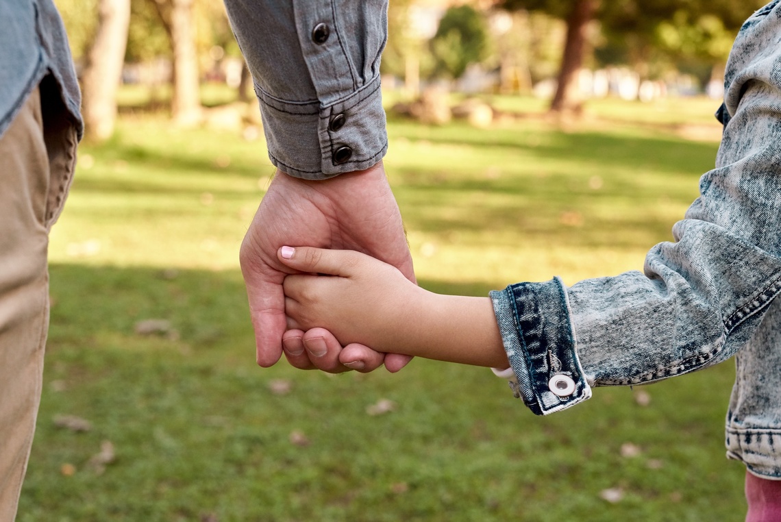 Ein Erwachsener und ein Kind halten sich an der Hand. 