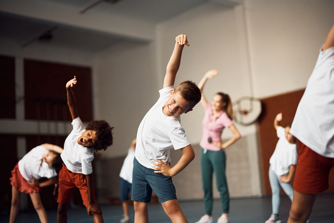 Kinder führen Sportübungen aus in einer Turnhalle