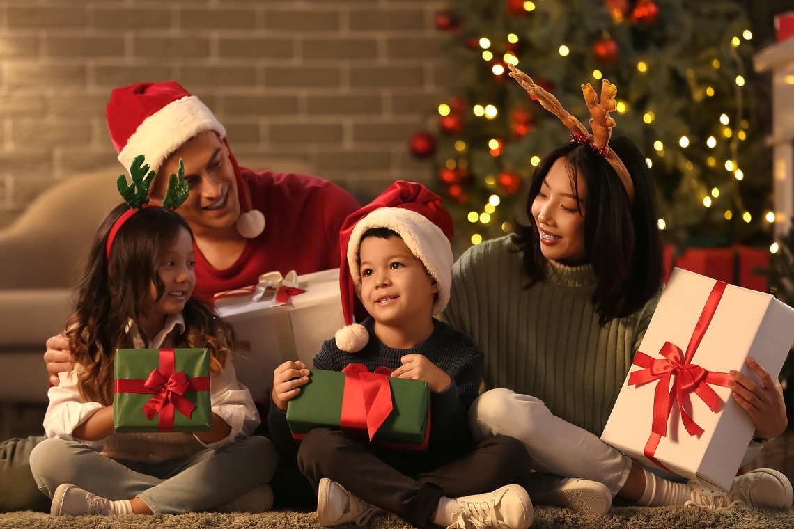 Familie sitzt vor einem Weihnachtsbaum.