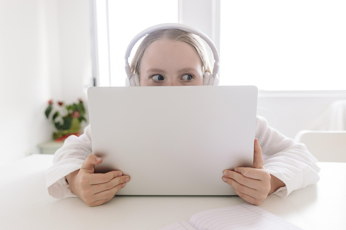 Kind mit Kopfhörern schaut über Laptop hinaus