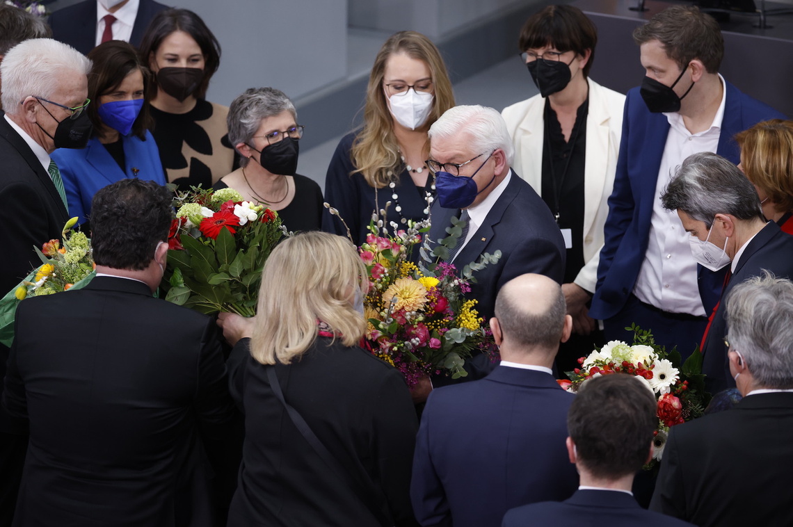Bundespräsident Frank-Walter Steinmeier mit Maske, umringt von Menschen, die ihm gratulieren und Blumen überreichen