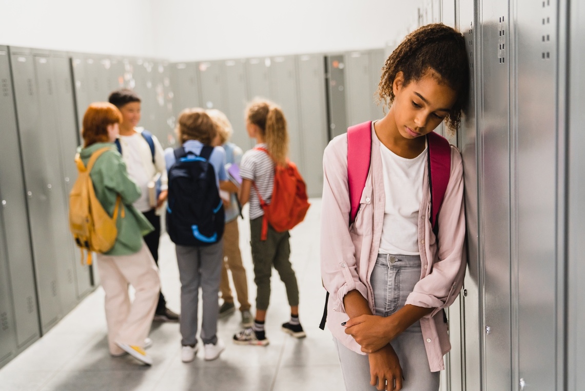 Trauriges Schulmädchen, die von ihren Klassenkameraden ignoriert wird