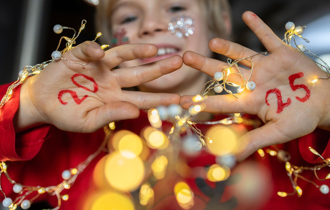 Ein Kind hält seine Hände in die Kamera, auf denen die roten Zahlen „20“ und „25“ geschrieben stehen