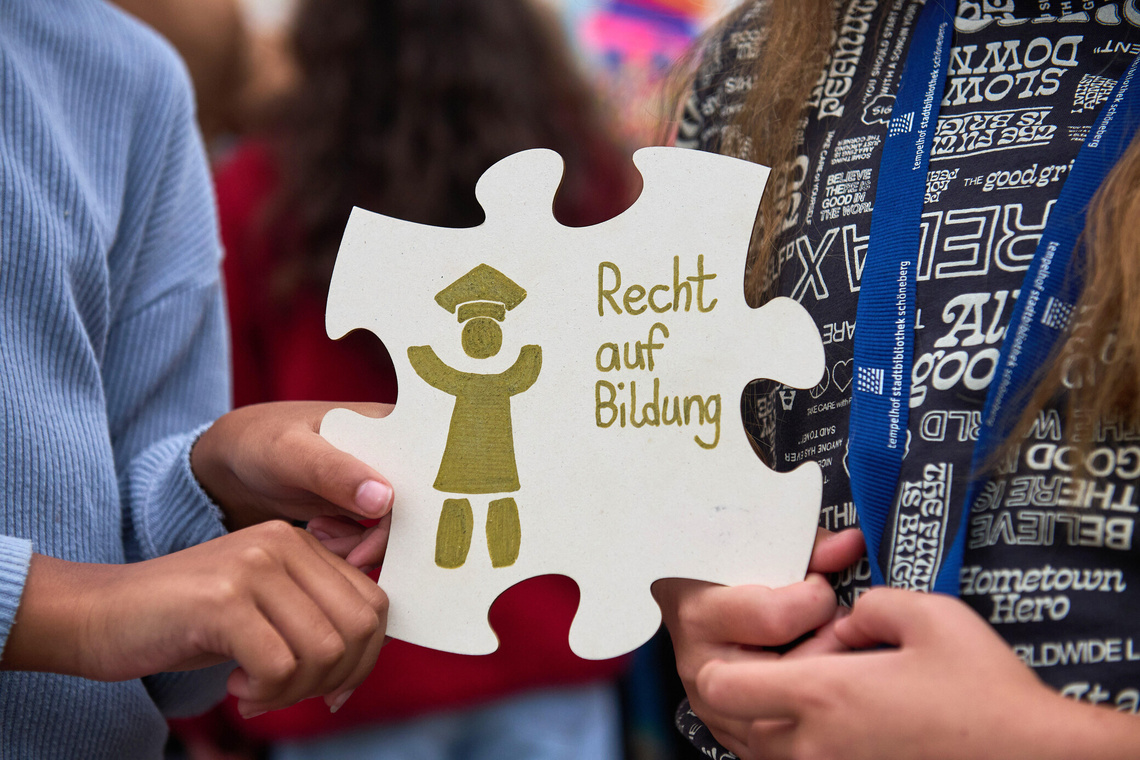 Kinderhände halten ein großes Puzzleteil mit Recht auf Bildung