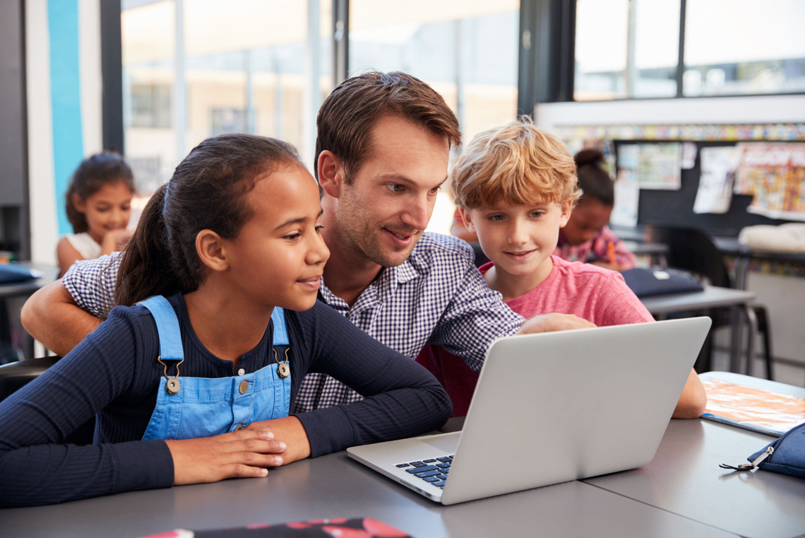 Lehrer mit zwei Kindern am Laptop 