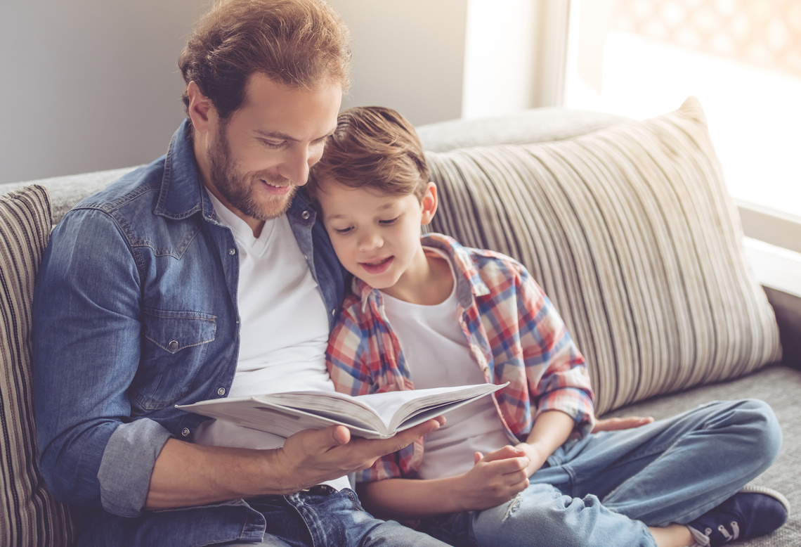Vater liest Sohn aus einem Buch vor