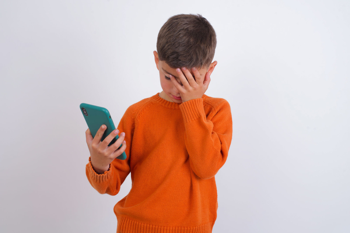 Trauriger Junge mit Smartphone in der Hand