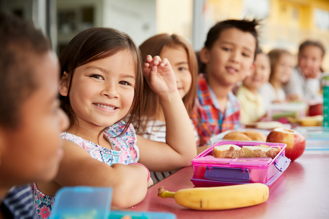 Kinder sitzen beim Mittagessen am Tisch