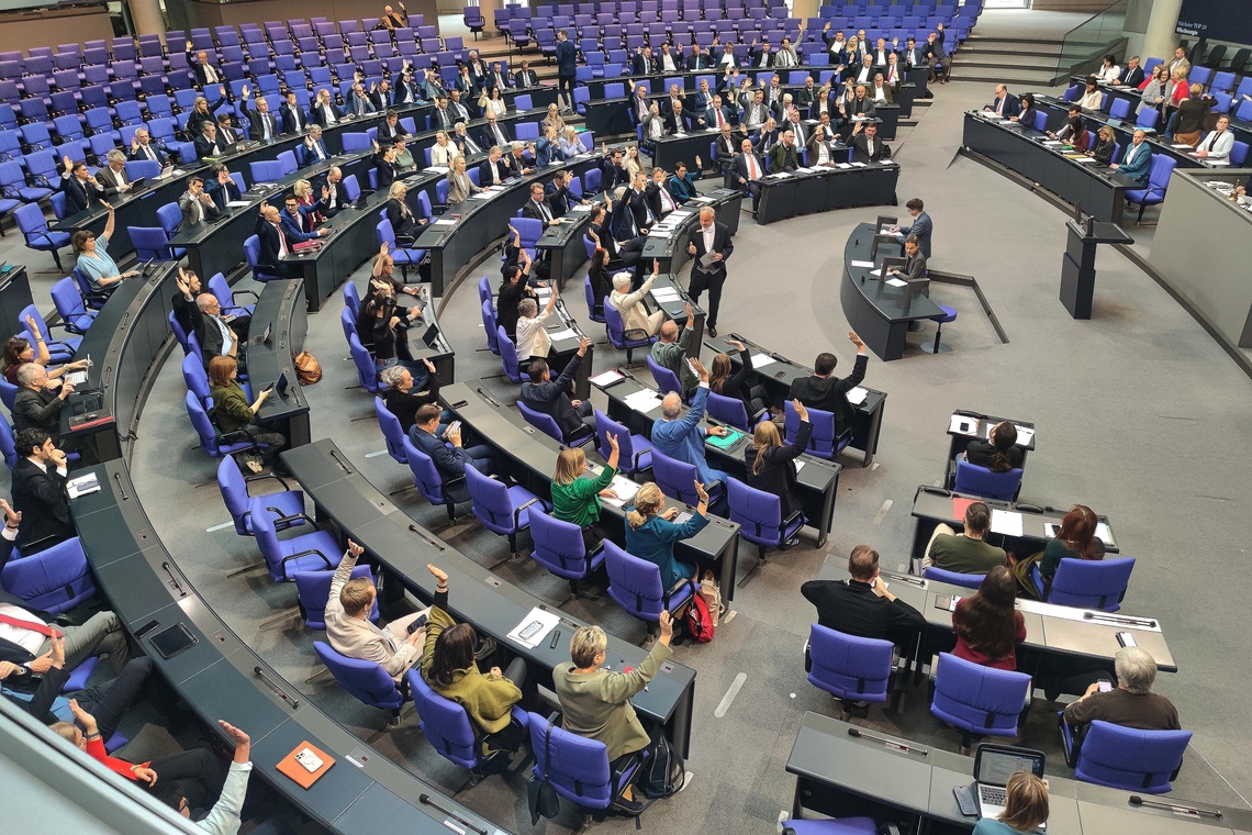 Menschen sitzen im Plenarsaal des Bundestags