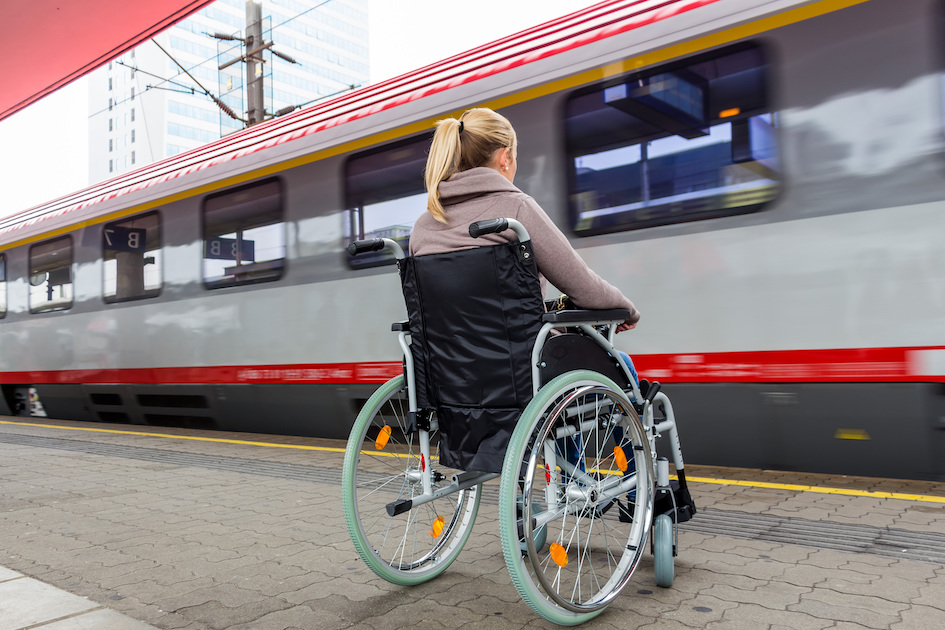 Frau im Rollstuhl auf einem Bahnhof