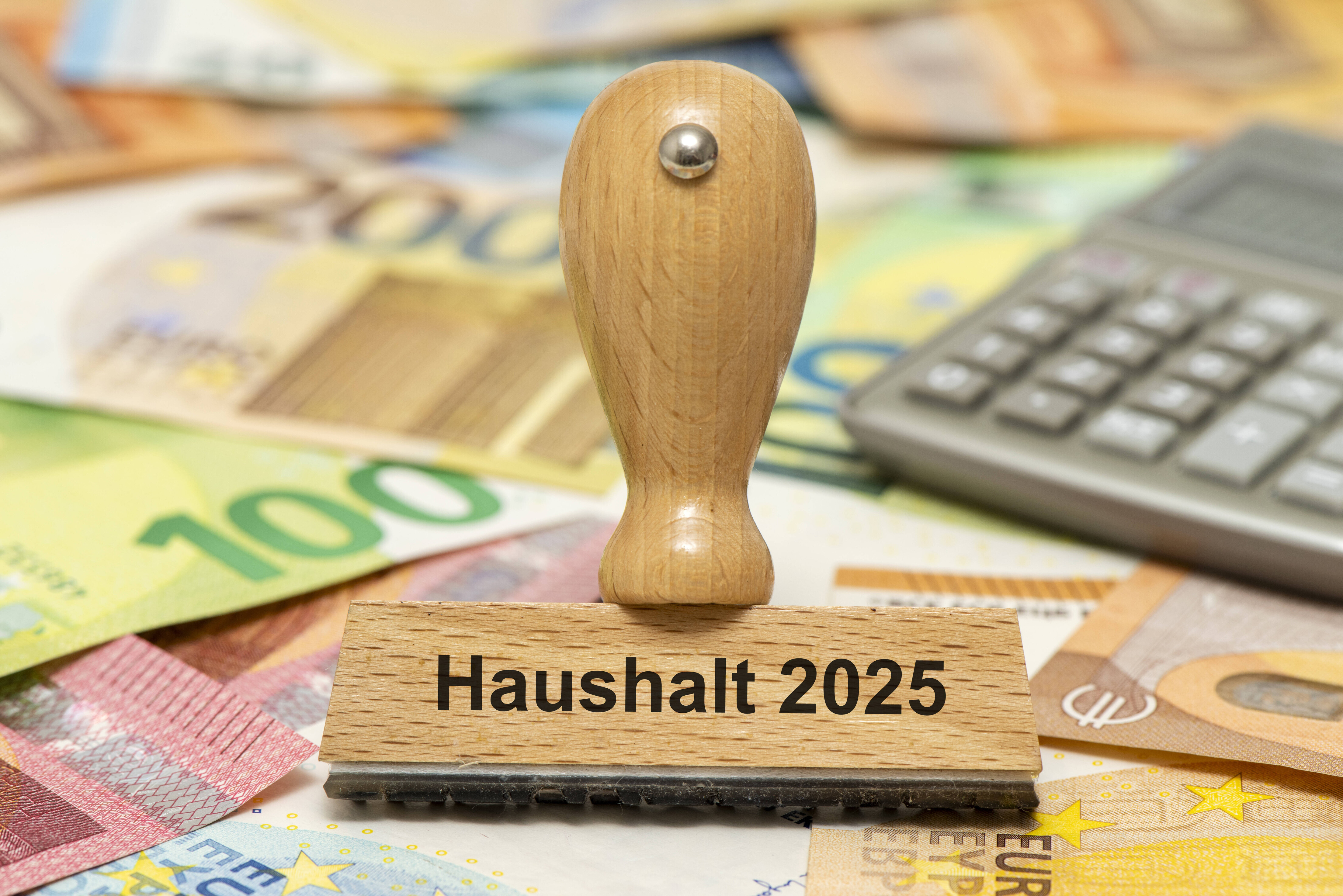 Geldscheine, Taschenrechner, Stempel mit Haushalt 2025