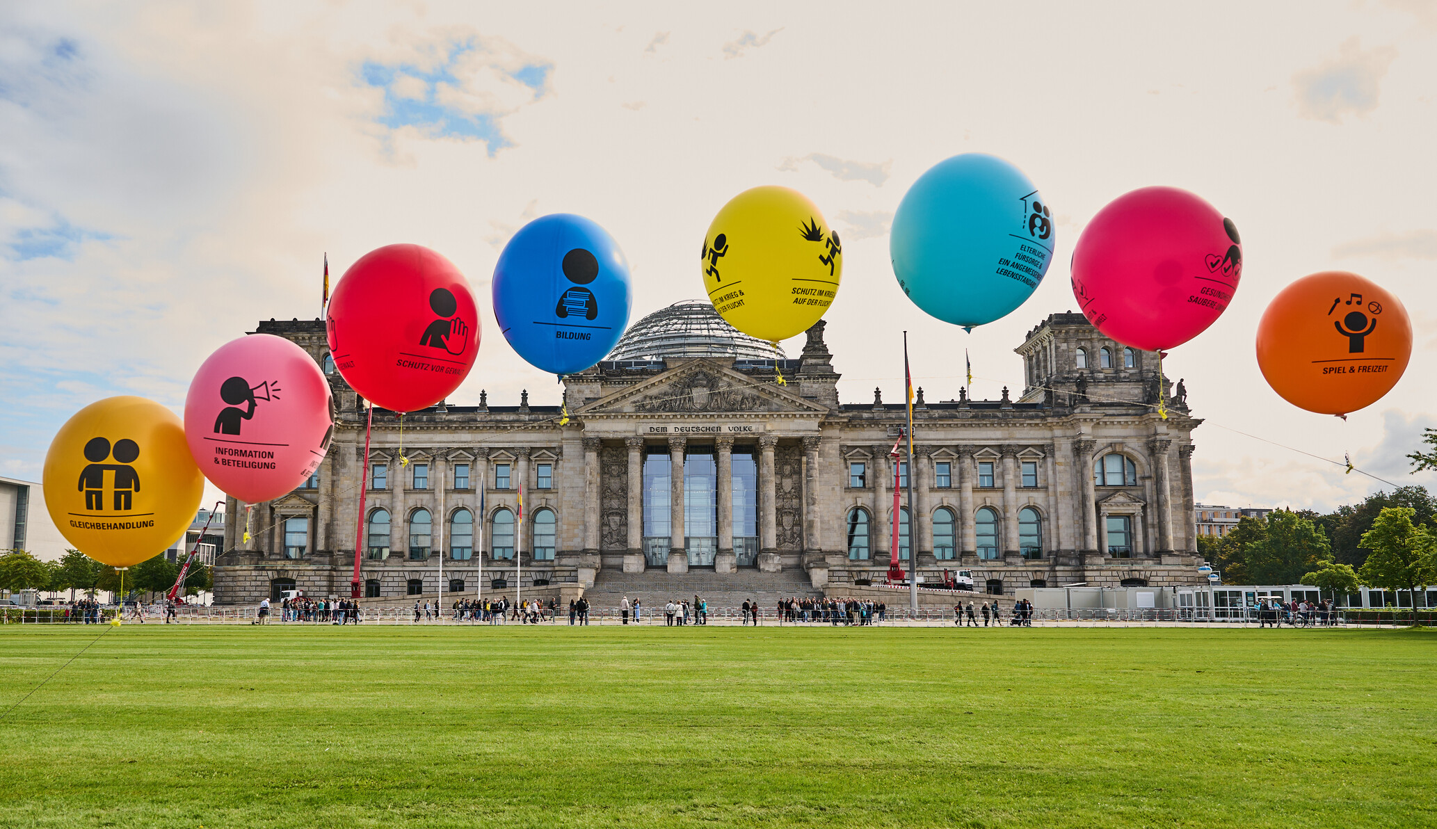 Bunte Luftballons mit ausgewählten Kinderrechten bedruckt auf der Wiese vor dem Bundestag